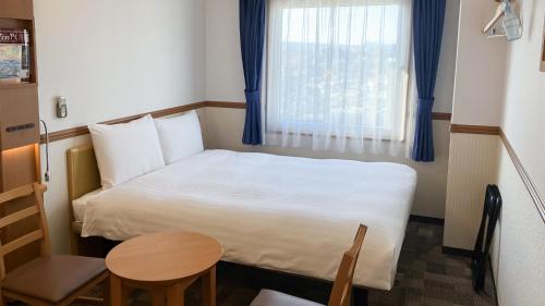a small room with a bed and a table and a window at Toyoko Inn Oita Nakatsu Ekimae in Nakatsu
