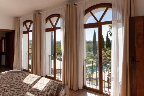 a bedroom with large windows and a bed and a balcony at Finca Can Rosa Ibiza, private pool, a nature getaway in Santa Gertrudis de Fruitera