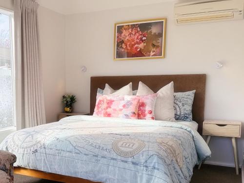 a bedroom with a large bed with pink pillows at Cozy & Sunny Room-Near City, Short Drive to City Center & Coast in Christchurch