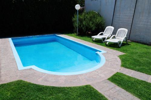 a swimming pool in a yard with two chairs at Hotel Almería San Rafael in San Rafael