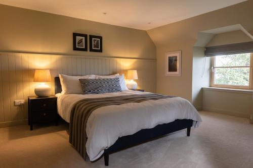a bedroom with a bed with two lamps and a window at Luxury Farmhouse, near Dornoch in The Mound