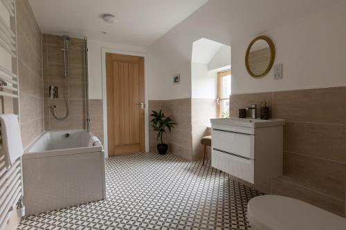 a bathroom with a tub and a sink and a mirror at Luxury Farmhouse, near Dornoch in The Mound