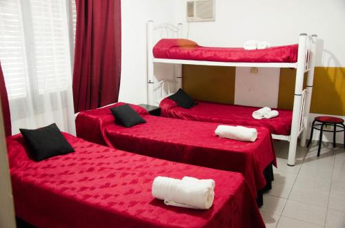 three beds in a room with red sheets at Hotel Almería San Rafael in San Rafael