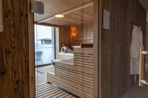a dressing room with wooden walls and a woman sitting in a chair at Seemöwe Wellnesshotel Swiss Quality in Güttingen