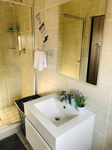 a bathroom with a white sink and a mirror at The blyde-Luxury one bedroom apartment in Pretoria