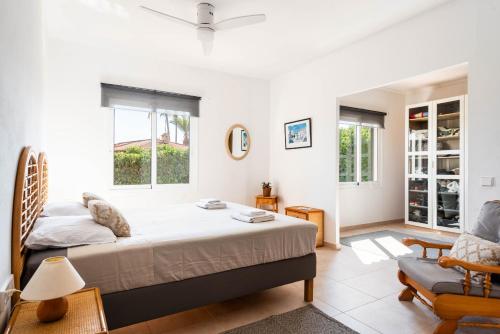 a bedroom with a large bed and a chair at Villa Margarita Punta Prima by Escape Home in Punta Prima