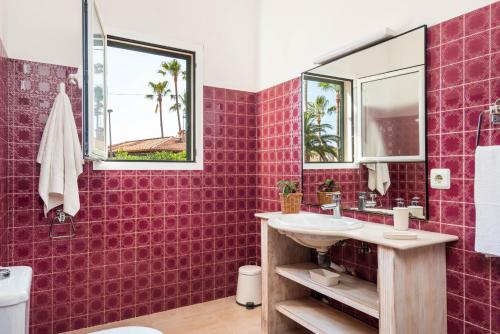 a bathroom with a red tiled wall at Villa Margarita Punta Prima by Escape Home in Punta Prima