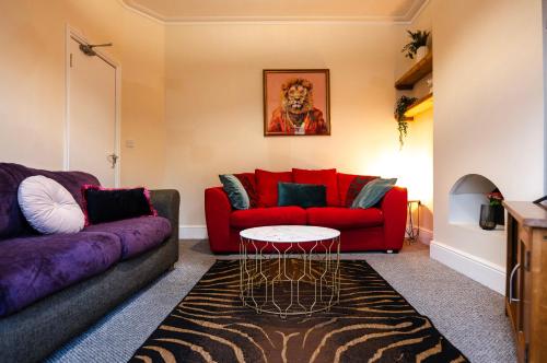 a living room with a red couch and a table at Gloucester 5 Bedroom Cosy Home-Work or Leisure in Gloucestershire