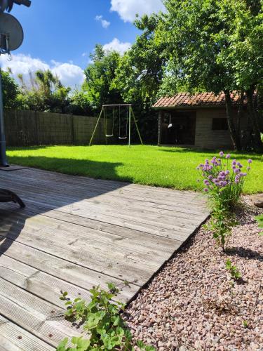 a wooden walkway with a playground in a yard at Le gîte des hallais in Bouelles
