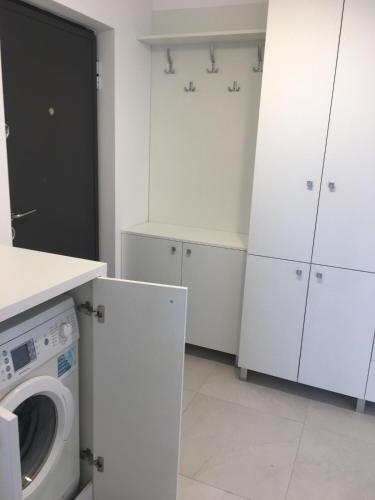 a kitchen with white cabinets and a washing machine at Two rooms Vivo Metro Amethyst in Floreşti
