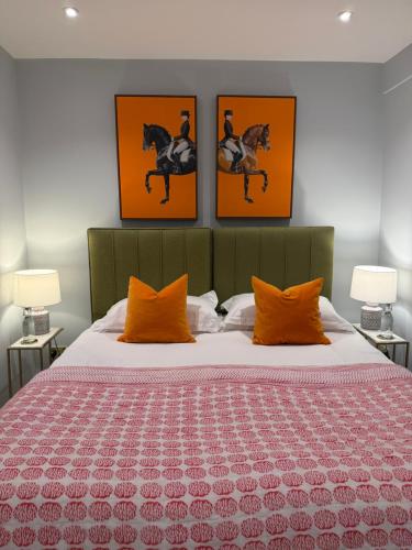 a bedroom with a bed with orange pillows and three paintings at The Broughton Townhouse in Edinburgh