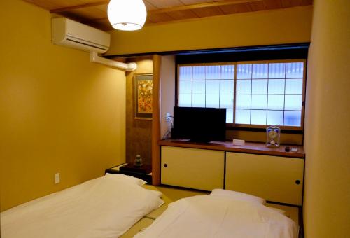 a small room with two beds and a window at 京宿日和 聚楽 Hiyori Juraku in Kyoto