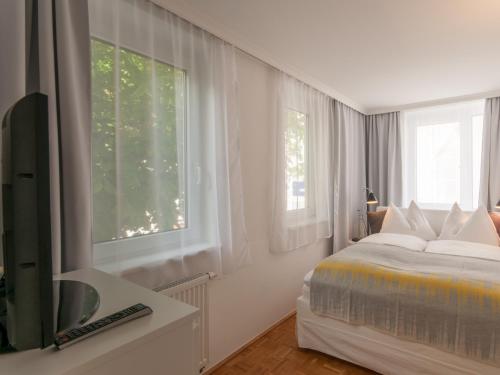 a white bedroom with a bed and a window at Design Apartment Zell am See in Zell am See