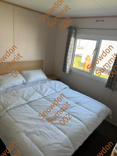 a bedroom with a bed with orange writing on it at Snowdon Summit 002 in Barmouth