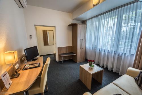 a room with a desk with a computer and a couch at Hotel Lousberg in Aachen