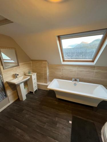 a bathroom with a tub and a sink and a window at Station apartment in Llanberis