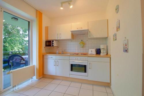a kitchen with white cabinets and a large window at Lilli Marleen WE 26 in Wremen