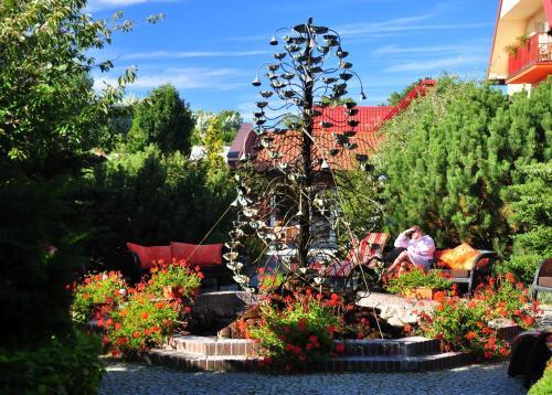 a woman sitting on a bench in a garden with flowers at Kormoran Medispa in Rowy