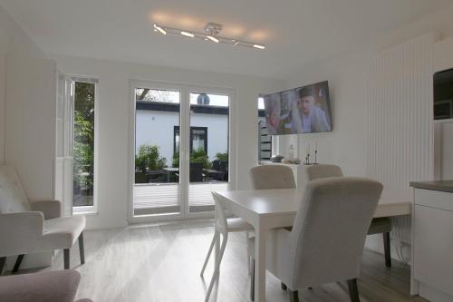 a white dining room with a white table and chairs at KW4 Haus Anna in Dorum-Neufeld