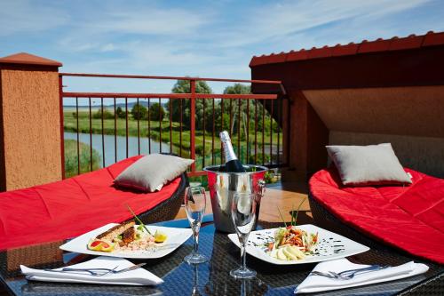a table with plates of food and wine glasses on a balcony at Kormoran Medispa in Rowy
