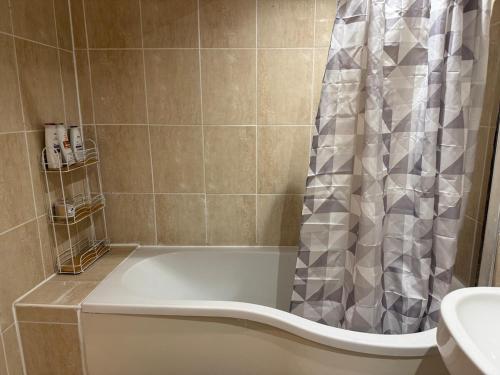 a bath tub with a shower curtain in a bathroom at London Heathrow Accommodation in Hillingdon