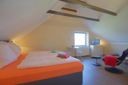 a bedroom with an orange bed and some chairs at Gästehaus Dorum 05 in Dorum
