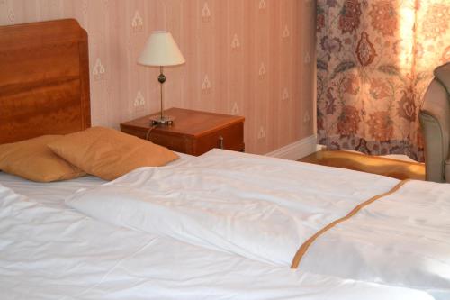 a white bed in a bedroom with a lamp on a table at Amals Stadshotell, BW Signature Collection in Åmål