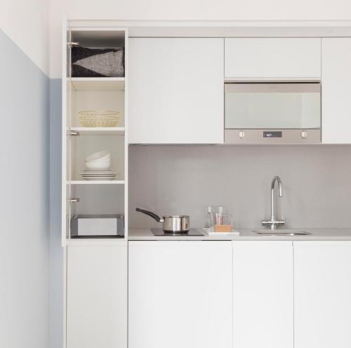 a white kitchen with white cabinets and a sink at Leman Locke in London