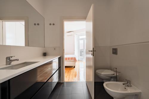 a white bathroom with a sink and a toilet at Eighteen21 Houses - Casa de São Paulo in Lisbon