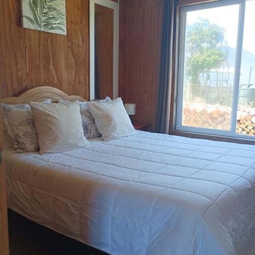 a bedroom with a large white bed with a window at CABAÑA HUALAIHUE AUSTRAL in Hornopiren