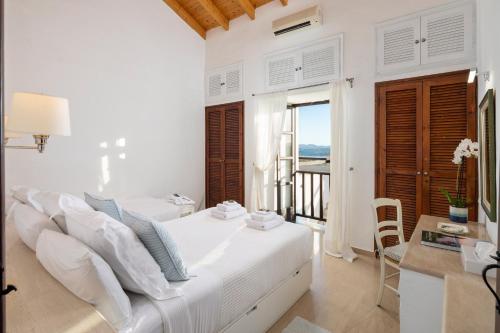 a white bedroom with a bed and a balcony at Spartilas Villas in Pyrgi