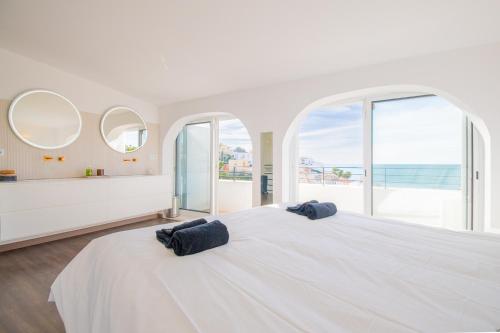 a white bedroom with a large white bed with two pillows on it at 14 Travessa das Naus in Carvoeiro