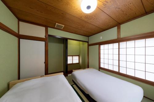 two beds in a room with two windows at Kotori Ayase in Tokyo