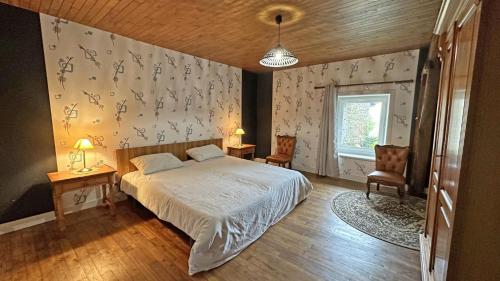 a bedroom with a bed and two chairs and a window at Les tâches in Pensol