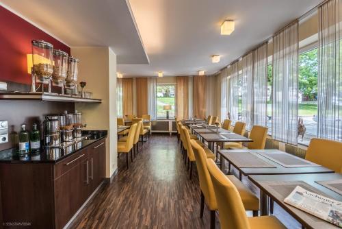 a restaurant with wooden tables and yellow chairs at Hotel Lousberg in Aachen