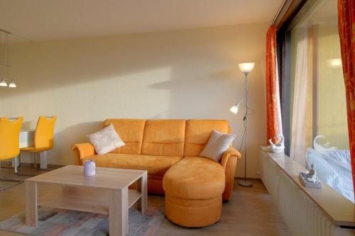 a living room with an orange couch and a table at Apartment 545 in Hohegeiß