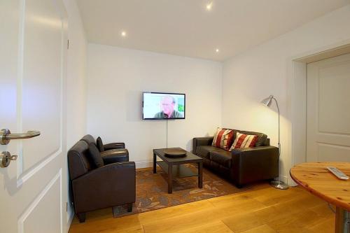 a living room with two chairs and a tv on the wall at NS 6 Strandläufer Wremen in Wremen