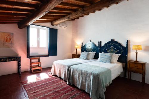 a bedroom with two beds and a large window at Eighteen21 Houses - Casa dos Condes in Cano