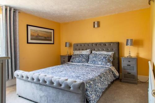 a bedroom with a large bed and yellow walls at Thyme Cottage in Beccles