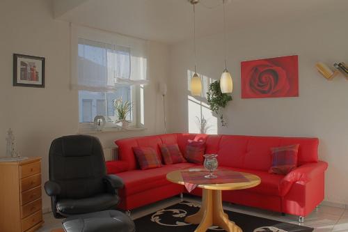 a living room with a red couch and a table at LT 33a Bungalow Max in Dorum-Neufeld