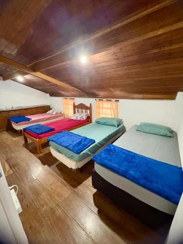 three beds in a room with wooden ceilings at Chácara do Paulinho in São Roque