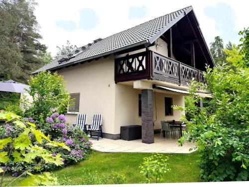 a house with a balcony and a table and chairs at Kiefernwäldchen in Byhlen