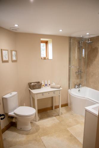 a bathroom with a toilet and a tub and a shower at The Cowshed in Hooe