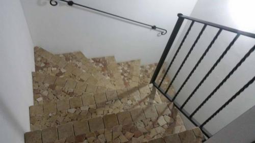 a staircase with a stone wall and a metal rail at Casa Allende in Bosa