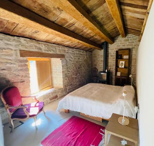 a bedroom with a bed and a chair and a window at Equisoain Ala Sur in Monreal