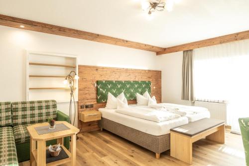 a bedroom with a large bed and a couch at Hotel Garni Schellenberg in Oberstdorf
