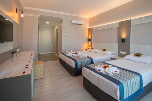 a hotel room with two beds with flowers on them at Silver Hotel in Side