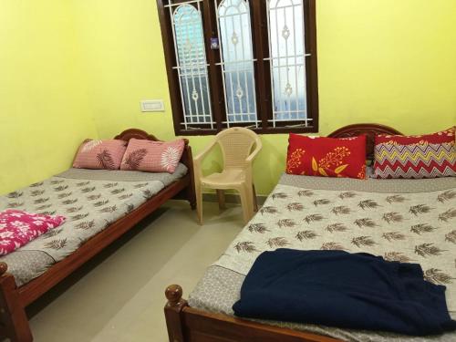a room with two beds and a chair in it at Nandy Delight Homestay in Kanyakumari