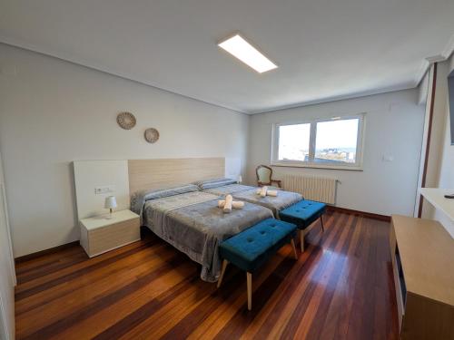 a bedroom with a large bed with two blue seats at Casa-Nova Centro in Sarria
