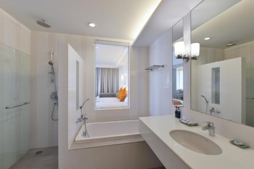 a bathroom with a sink and a tub and a mirror at Hisea Huahin Hotel in Hua Hin